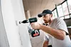 A man is using a cordless drill to make a hole in a wall. Produktbild-Vorschau
