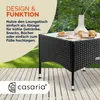 A polyrattan garden table with a glass top, set on a wooden deck with grass and trees in the background. Croissants and coffee are on the table. Produktbild-Vorschau