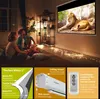 A family is watching a movie on a projector screen in a dimly lit room, with decorative lights on the floor. Produktbild-Vorschau