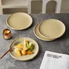 Plates with food on a table, next to a candle and a recipe book. Produktbild-Vorschau
