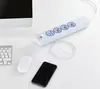 A white power strip with multiple outlets and USB ports is shown on a white desk next to a computer monitor, keyboard, mouse, and a smartphone being charged. Produktbild-Vorschau