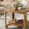A round wooden coffee table with two shelves, decorated with a vase of flowers and books. Produktbild-Vorschau