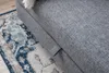 A close-up view of a grey sofa next to a rug. Produktbild-Vorschau