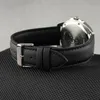 A close-up side view of a black leather watch strap with a silver buckle. Voir les images du produit