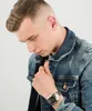 A man wearing a denim jacket, looking down at his watch. Náhled obrázku produktu