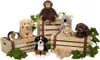 A collection of stuffed animals, including a koala, monkey, dogs, rabbits, and a guinea pig, are arranged on wooden crates with some greenery. Produktbild-Vorschau