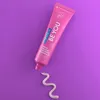 A pink tube of Curaprox toothpaste is shown on a purple background, with a swirl of toothpaste on the surface below it. Anteprima dell’immagine prodotto