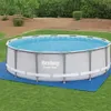 An above-ground swimming pool filled with water, set up on a blue mat on a grassy lawn. Produktbild-Vorschau