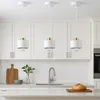 Three white and gold pendant lights hang over a kitchen counter with a sink and a cutting board. Náhled obrázku produktu