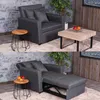 A dark gray sofa bed is shown in two states: as a sofa and as a bed. It is placed on a fluffy rug in a room with a stone wall and wooden accents. Produktbild-Vorschau