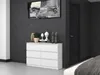 A white dresser with six drawers is shown in a bedroom setting with a dark gray wall and a dark wooden door. Anteprima dell’immagine prodotto