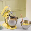A yellow KitchenAid stand mixer is shown on a countertop with a bowl of batter and a spatula in another bowl. Produktbild-Vorschau