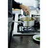 A person is adding herbs to a pot on a gas stove. Náhled obrázku produktu