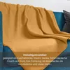 A yellow blanket draped over a blue sofa. Produktbild-Vorschau