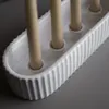 A close-up view of a white ceramic candle holder with three beige candles inserted. Produktbild-Vorschau
