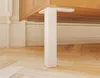 A close-up view of a white furniture leg attached to a wooden cabinet, resting on a wooden floor. Produktbild-Vorschau