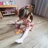 A young girl is playing with a toy kitchen set on the floor. Anteprima dell’immagine prodotto