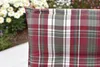 A close-up of a plaid cushion on a chair, with flowers in the background. Produktbild-Vorschau