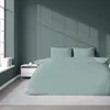 A bed with mint-colored striped bedding is shown in a room with green walls and a window casting shadows. Podgląd zdjęcia produktu