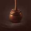 A close-up of a chocolate truffle being covered in melted chocolate. Anteprima dell’immagine prodotto