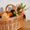 A wicker picnic basket filled with fruit and flowers. Produktbild-Vorschau