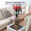 A person is emptying a vacuum cleaner's dustbin into a separate container in a living room setting. Voir les images du produit