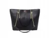 A black leather tote bag with gold chain straps is shown against a white background. Náhľad obrázku produktu