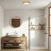 A modern bathroom with a wooden vanity, a round mirror, and a walk-in shower. Produktbild-Vorschau