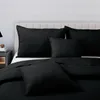 A bed with black quilted pillows and a comforter. Produktbild-Vorschau