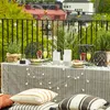 A decorated table on a balcony with string lights and pillows. Náhled obrázku produktu