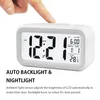 A finger presses the top of a digital alarm clock, displaying the time, date, and temperature. Text below describes its features. Náhled obrázku produktu