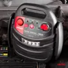 A black jump starter is placed on top of a car battery in an engine bay. Podgląd zdjęcia produktu