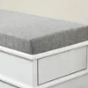 A close-up view of the top corner of a bench with a grey fabric cushion and a white wooden drawer. Produktbild-Vorschau