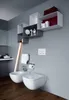 A modern bathroom with a toilet, bidet, and shelving unit. Produktbild-Vorschau