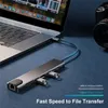 A USB hub is connected to a laptop, with a camera in the background. Produktbild-Vorschau