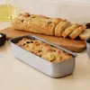 A loaf pan with bread in it and a sliced loaf of bread on a cutting board. Voir les images du produit