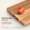 A close-up of a wooden cutting board with a tomato slice and text overlays describing its features. Produktbild-Vorschau