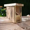 A wooden smoking chamber sits on a wooden surface, with a blurred green background. Náhled obrázku produktu