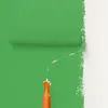 A paint roller is shown applying green paint to a white wall. Produktbild-Vorschau