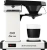A white Moccacoffee maker with a black filter holder and a white cup with a black grip. Produktbild-Vorschau
