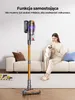 A woman is sitting on a couch holding a cat, with a cordless vacuum cleaner standing upright in front of her. Podgląd zdjęcia produktu