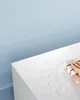 A hand is wiping water off a white surface with a cloth. Náhled obrázku produktu