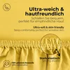 A close-up marketing image of yellow fabric, likely a bedsheet or similar textile product, highlighting its softness, skin-friendliness, and elastic features. Produktbild-Vorschau