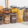 A collection of clear plastic food storage containers filled with various dry goods like pasta, beans, and nuts, arranged on a countertop. Podgląd zdjęcia produktu