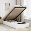 A white ottoman bed with the mattress base lifted to reveal storage space underneath. Voir les images du produit