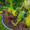 A beautifully landscaped garden bed with various plants and mulch. Produktbild-Vorschau