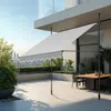 A modern balcony with an awning extended over a dining table and chairs, overlooking a city skyline. Produktbild-Vorschau
