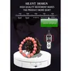 A product shot of a white rotating display stand with a bracelet and pinecone on it, overlaid with marketing text and a graphic illustrating sound decibels and a sound meter. Náhled obrázku produktu