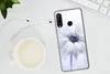 A smartphone case with a floral design is placed on a white desk next to a cup of coffee and earphones. Produktbild-Vorschau