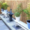 A garden scene with bamboo plants, benches, and a Buddha statue. Produktbild-Vorschau